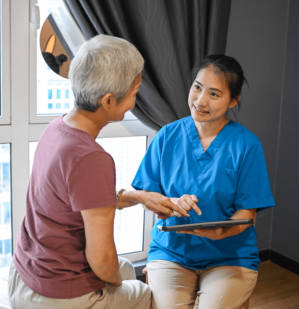 A nurse consulting with an elderly woman using a tablet.